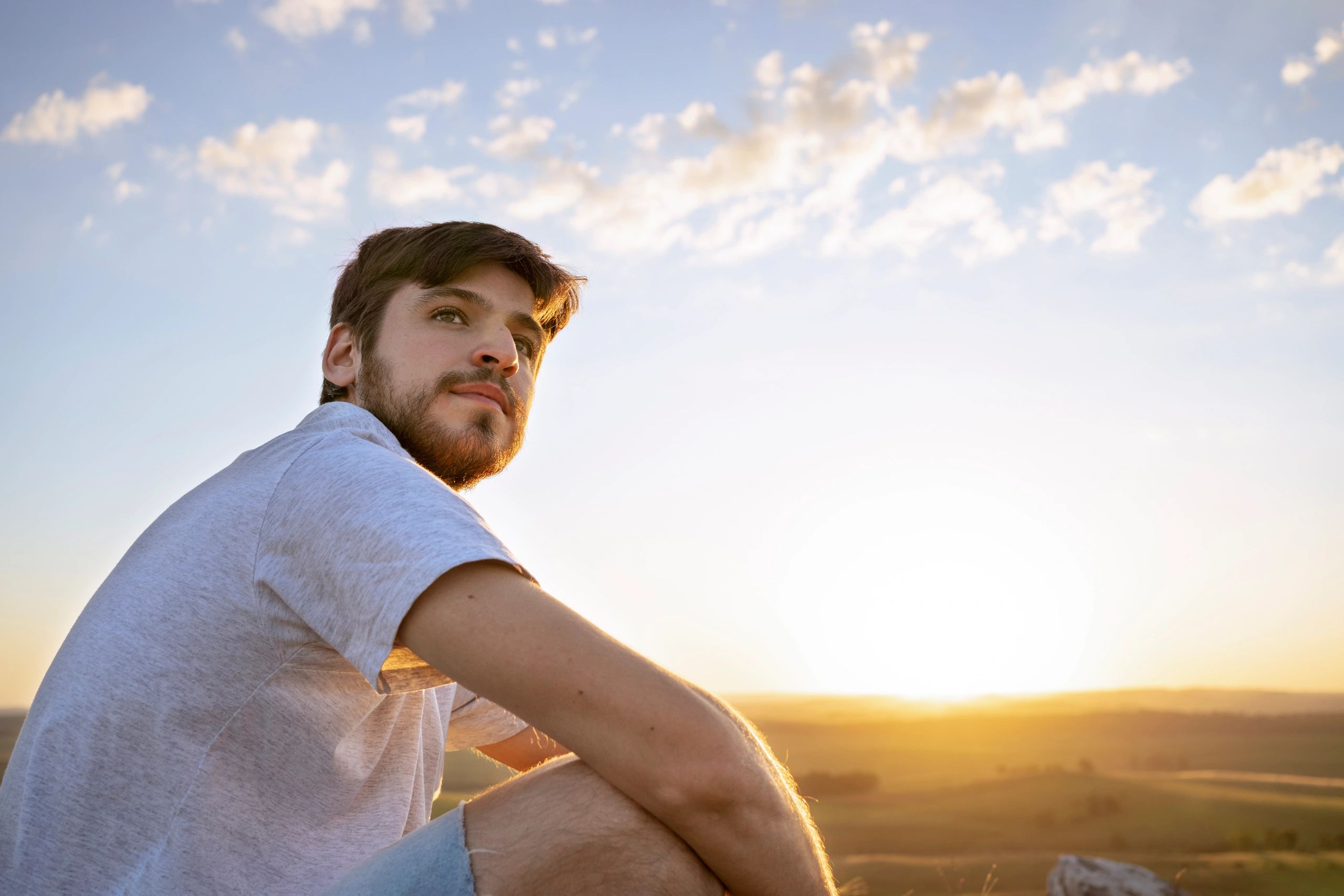 Man standing on a mountain at sunset looking toward the horizon