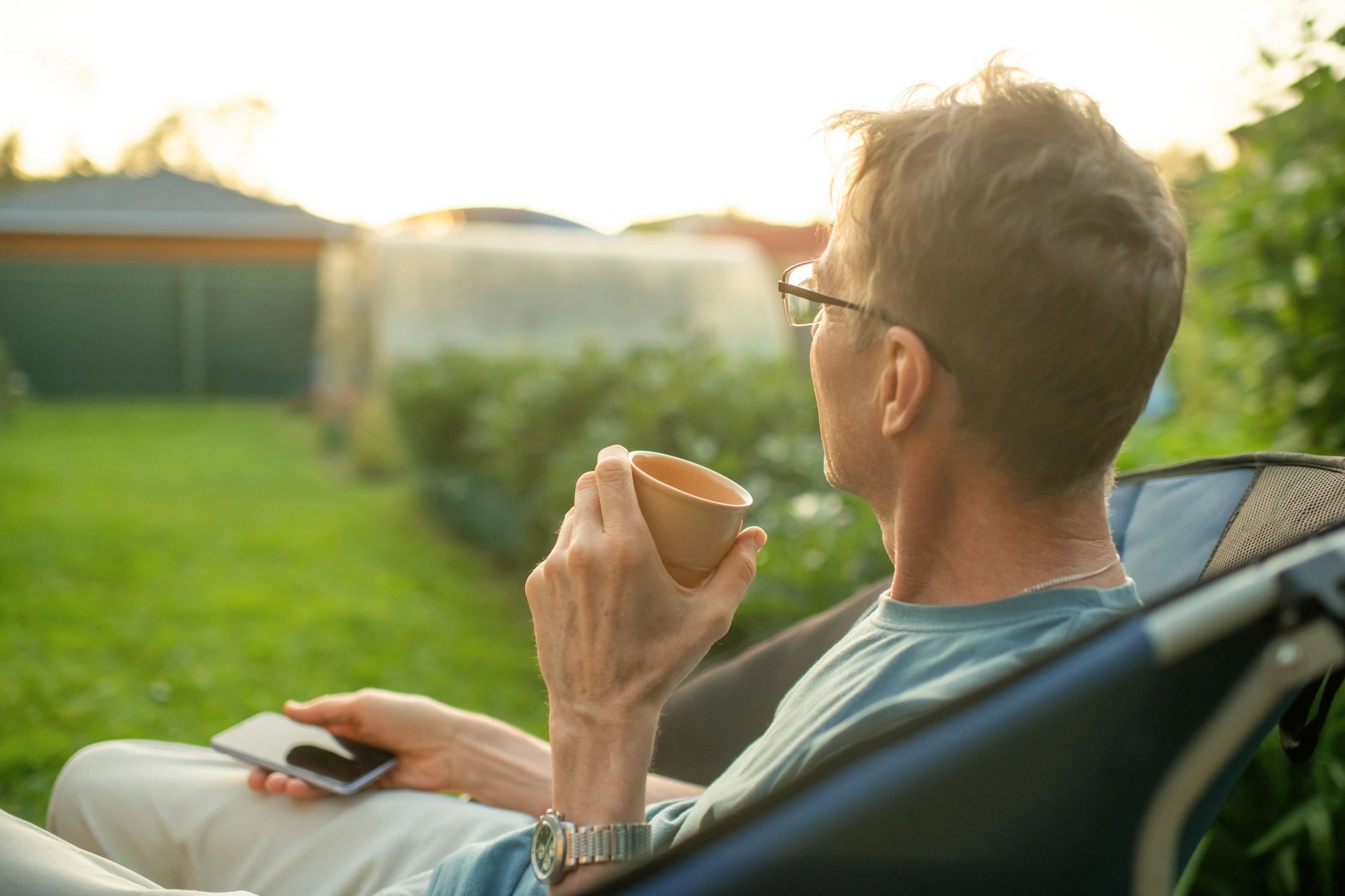 Man outdoors reflecting with tea and smartphone