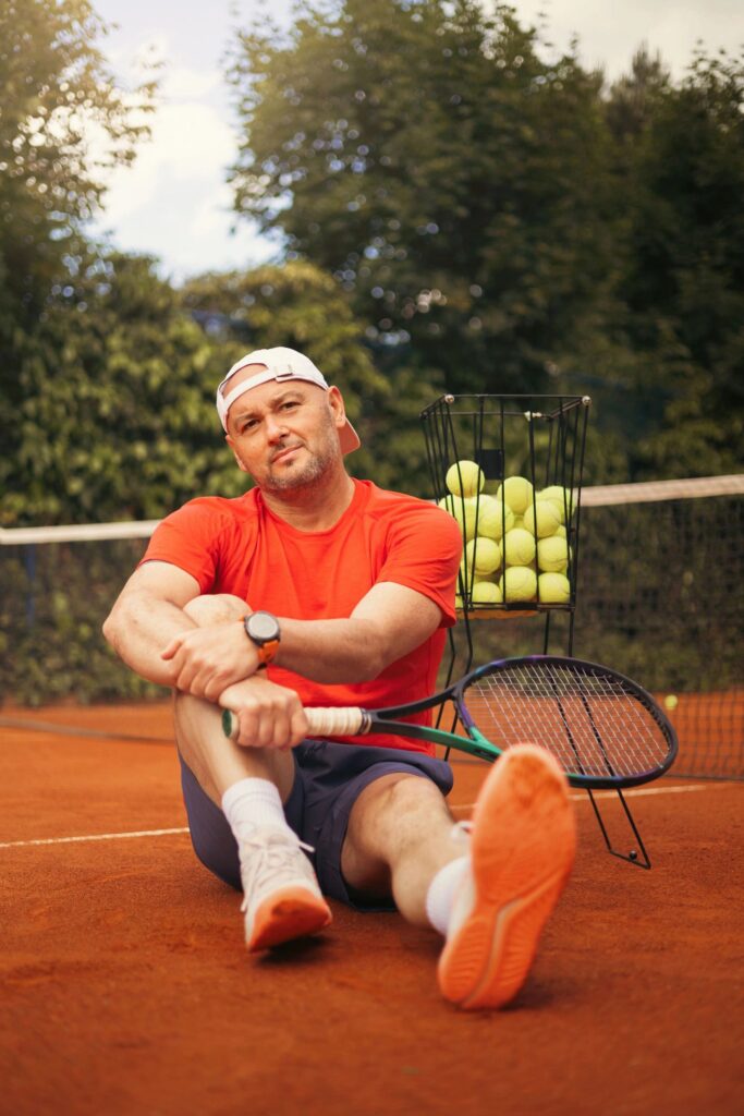 Tennis coach holding a racket on a clay court, professional sports setting with focused confident posture,
